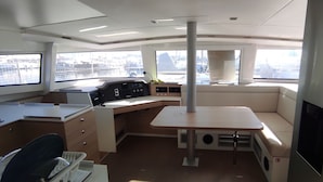 Interior de un barco con escritorio, panel de control y zona de estar.