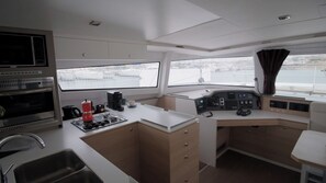 Eine kompakte Küche mit Herd, Kaffeemaschine und Blick auf das Wasser.
