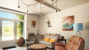 Una sala de estar con sofá, sillones, una mesa de centro, lámpara y obras de arte en las paredes.