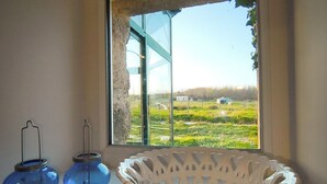 Una habitación con un ventanal grande, una cesta blanca y dos portavelas azules.