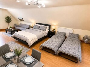 Habitación de hotel con dos camas, zona de comedor y ventilador de techo.