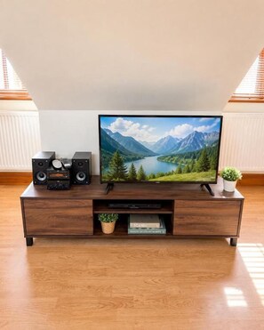 Un mueble de madera con un televisor de pantalla plana, parlantes y una planta pequeña.