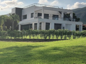A modern two-story building with a flat roof, large windows, and a balcony. - Golf course villa sleeping 8–10 with ocean views, 8 minutes from the beaches (Bonmont Terres Noves)