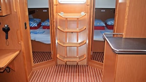 A compact RV interior with a kitchenette, a foldable bed, and a small seating area. - Sun-Kissed Sailing Adventure in Split, Croatia (Kaštel Gomilica)
