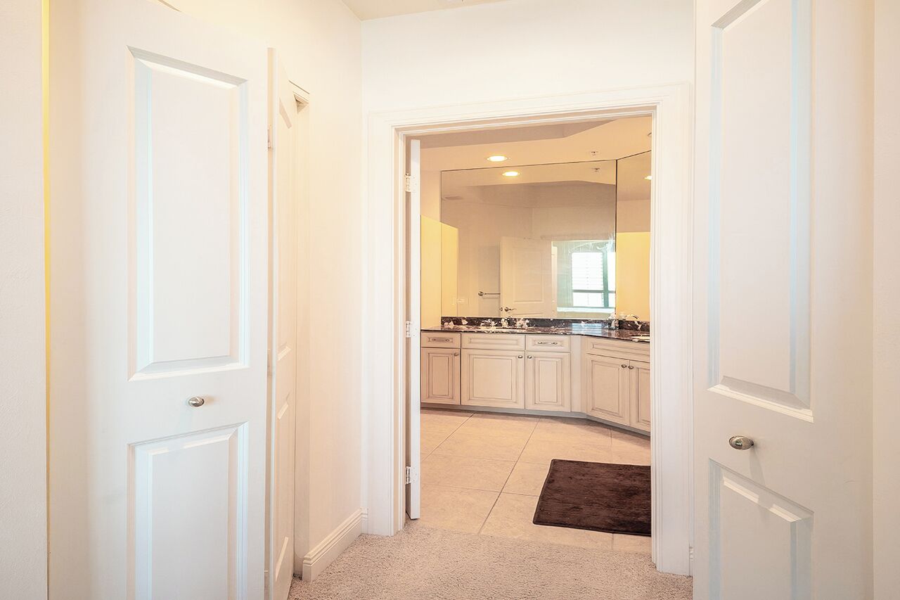 A hallway leading to a kitchen with white cabinetry and a dark rug.