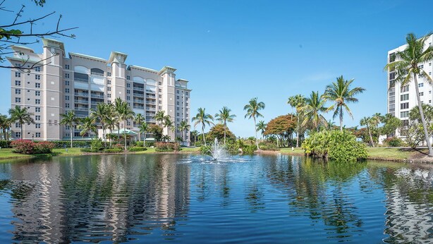 Een hotel met een groot waterpartij in de binnenplaats, omringd door palmbomen en een heldere lucht.