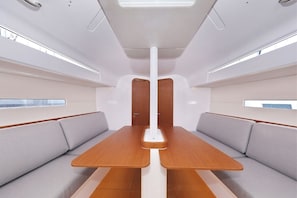 En modern inredning med ett stort bord i mitten, bekväma sittplatser och ett högt tak med takfönster.