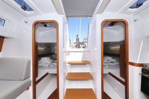 Een compact interieur met een centrale doorgang, houten trappen en uitzicht op het dek.