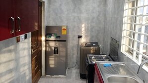 Cocina compacta con refrigerador, estufa y pileta, que cuenta con una ventana y una puerta con manija.