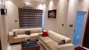 Una sala de estar con un sofá color beige, una mesa de centro de madera y un aire acondicionado instalado en la pared.