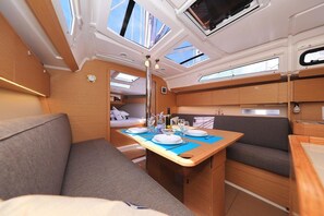 A compact galley with a dining table set for two, a small kitchenette, and a seating area with a sofa. - Sun-Kissed Sailing Adventure in Istria, Croatia (Pula)