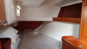 A compact cabin with a bed, a small wooden bench, and a window with wooden shutters.