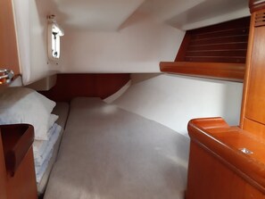 A compact cabin with a bed, a small wooden bench, and a window with wooden shutters.