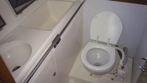 A small bathroom with a toilet, a shower stall, and a window.