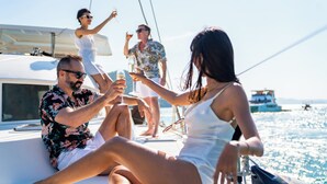 Un grupo de personas en un yate, con vista despejada al mar y otros barcos al fondo.
