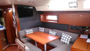 Un interior pequeño con una mesa, asientos, un panel de control y una televisión.