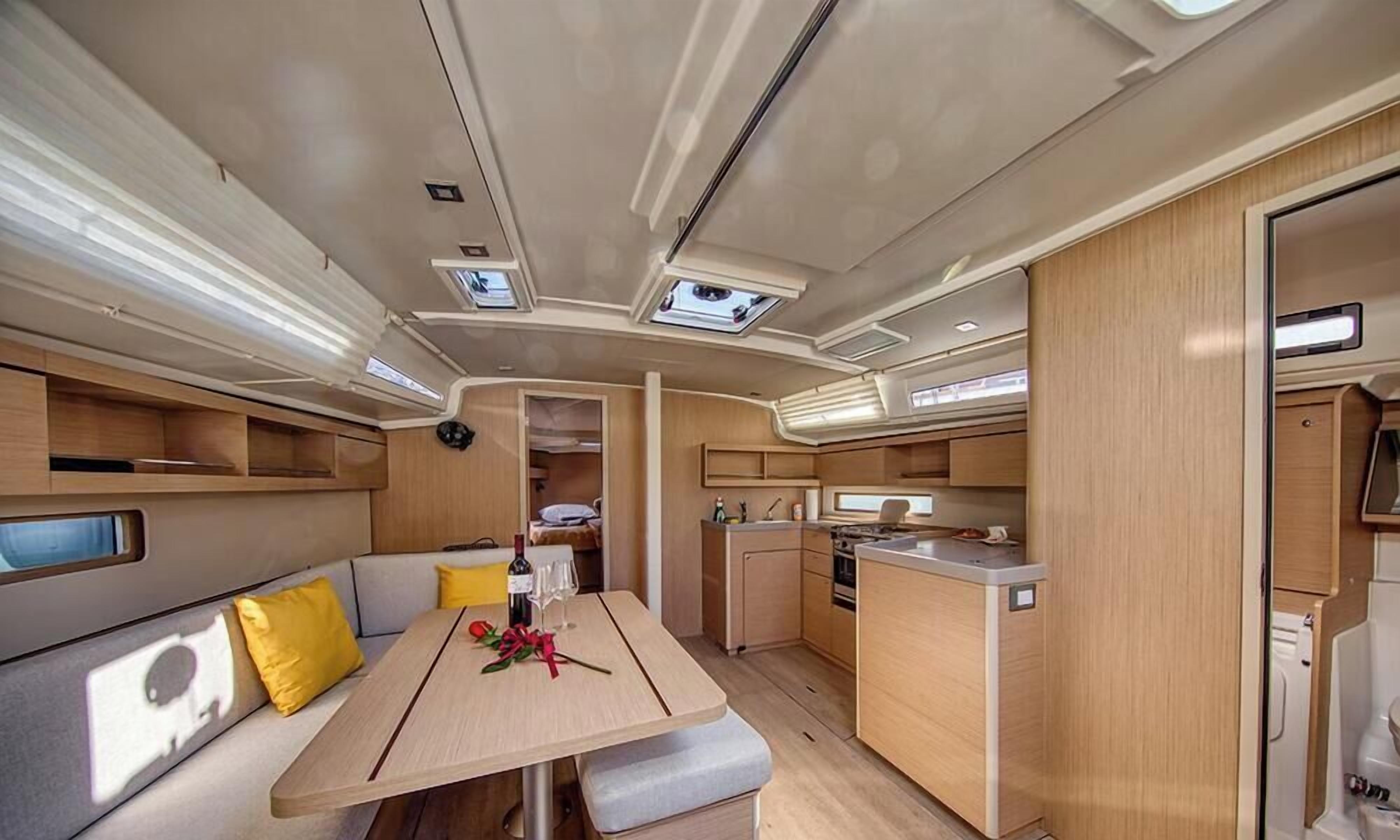 A compact RV interior with a dining area, kitchenette, and a small sleeping space.