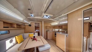 Ein kompaktes Wohnmobil-Interieur mit Essbereich, Küchenzeile und einer kleinen Schlafgelegenheit.