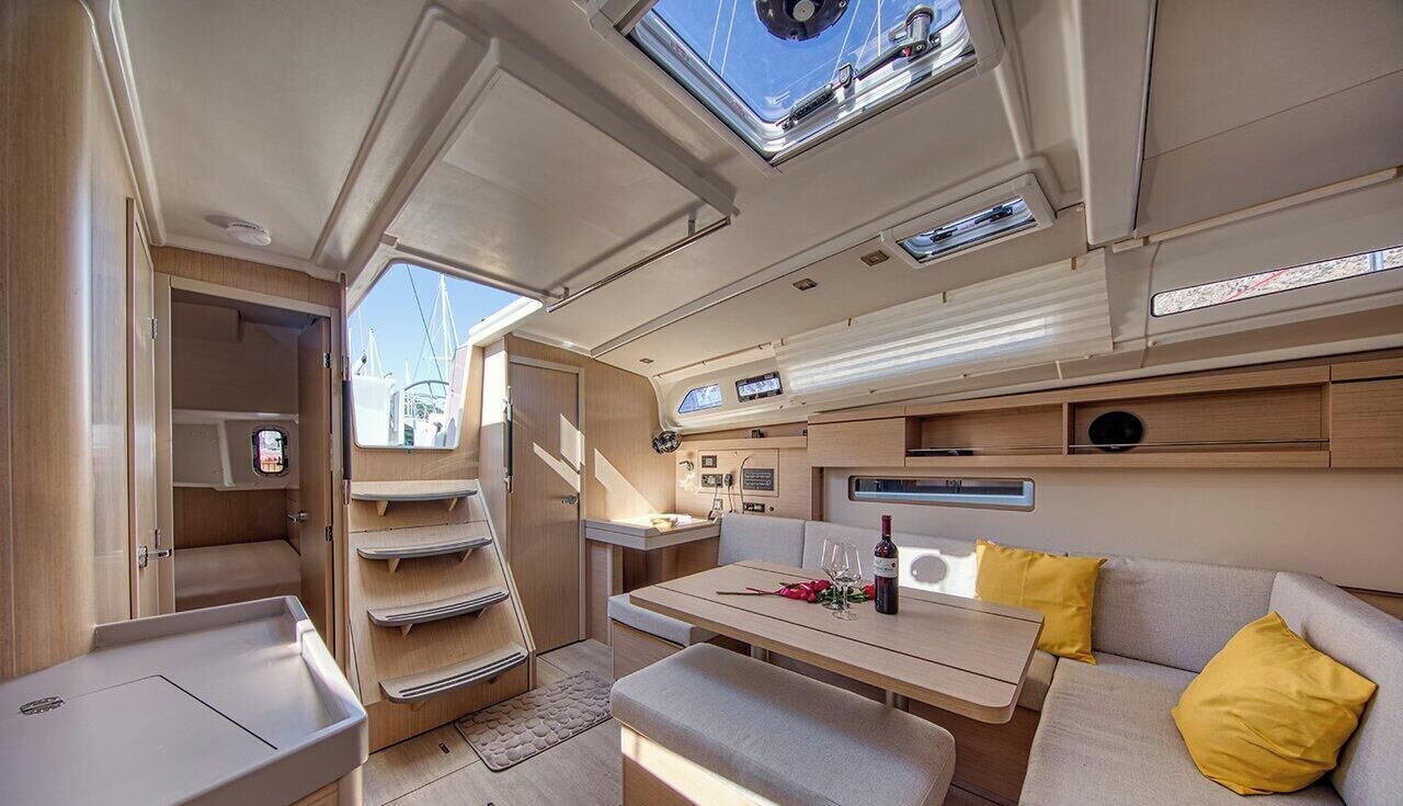 Un intérieur bien éclairé, avec un coin repas, un canapé doté de coussins jaunes et une lucarne au plafond.