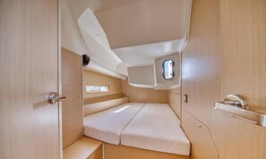 Un interior reducido con una cama, un ventanal pequeño y una puerta.