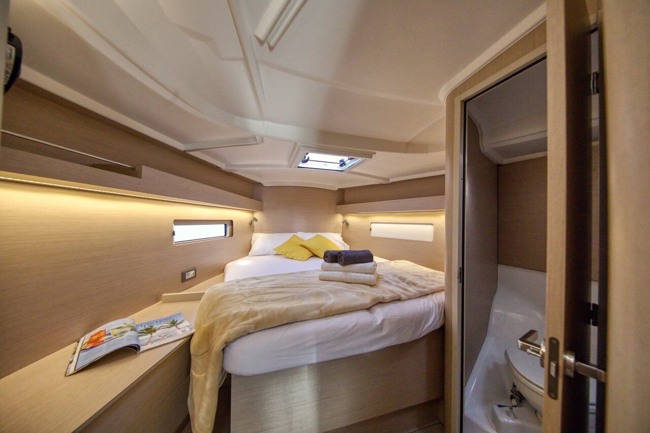 A compact bedroom with a bed, bedside table, and a small window.