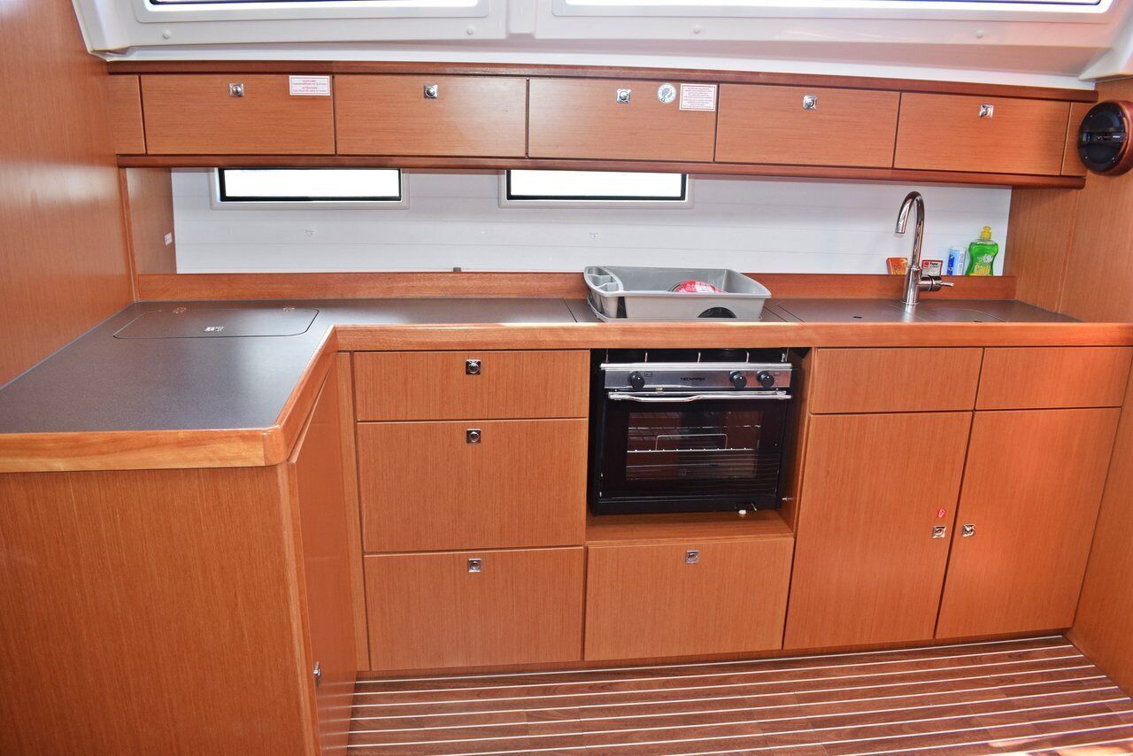 Eine kleine Küche mit Holzausbau, einer Edelstahl Arbeitsplatte, einem eingebauten Backofen und einem Spülbecken.