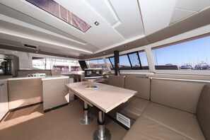 A modern galley with a central table, seating, and a view of the marina. - Sun-kissed Sailing Adventure in Split-Dalmatia, Croatia (Trogir)