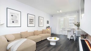 A modern living room with a beige sectional sofa, a white coffee table, and framed Bauhaus artwork on the wall. - Unique 2-Bedroom Apartment Balcony Parking (Poznań)