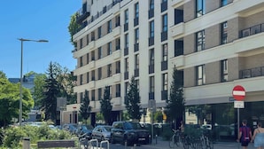 A multi-story building with balconies, parked cars, and a no entry sign. - Unique 2-Bedroom Apartment Balcony Parking (Poznań)
