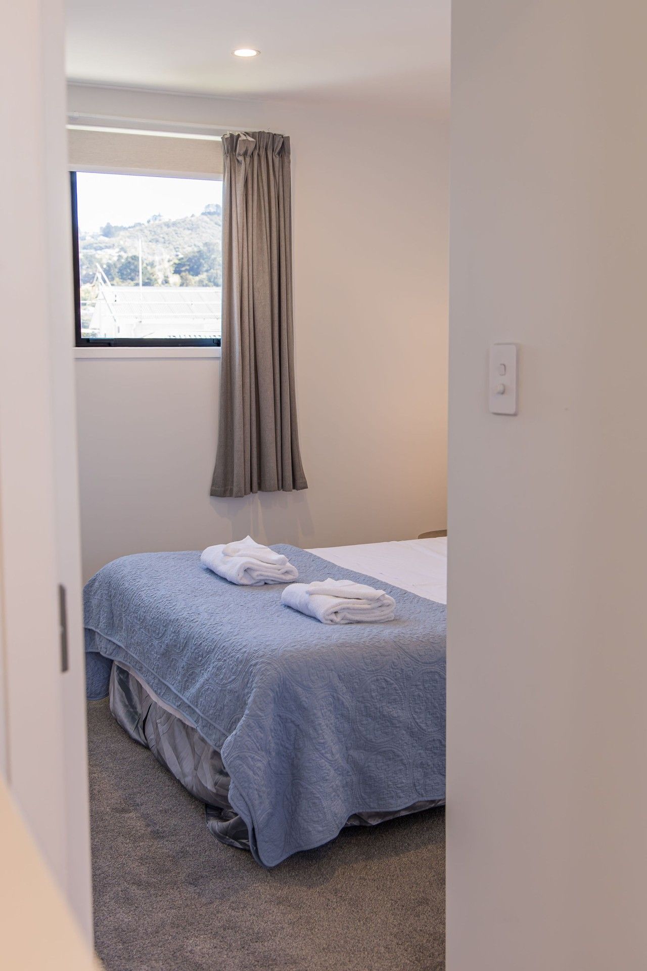 A bedroom with a bed, a window with curtains, and a carpeted floor.