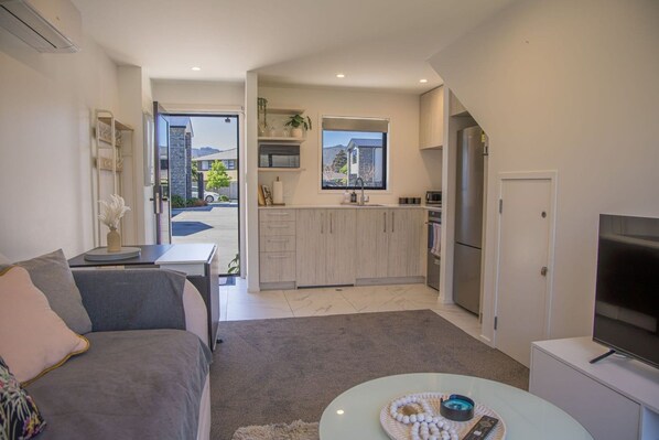 A modern apartment with a living room, kitchenette, and a view of the outside.