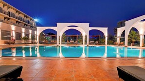 A swimming pool with a tiled deck, surrounded by white arches and outdoor seating. - Sunday Resort & Spa Manesar Gurugram (Taoru)