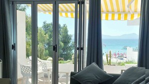 A room with a sliding glass door leading to an outdoor area with a patio, a white chair, and a table. - Mar Esmeralda Apartment (Alcúdia)