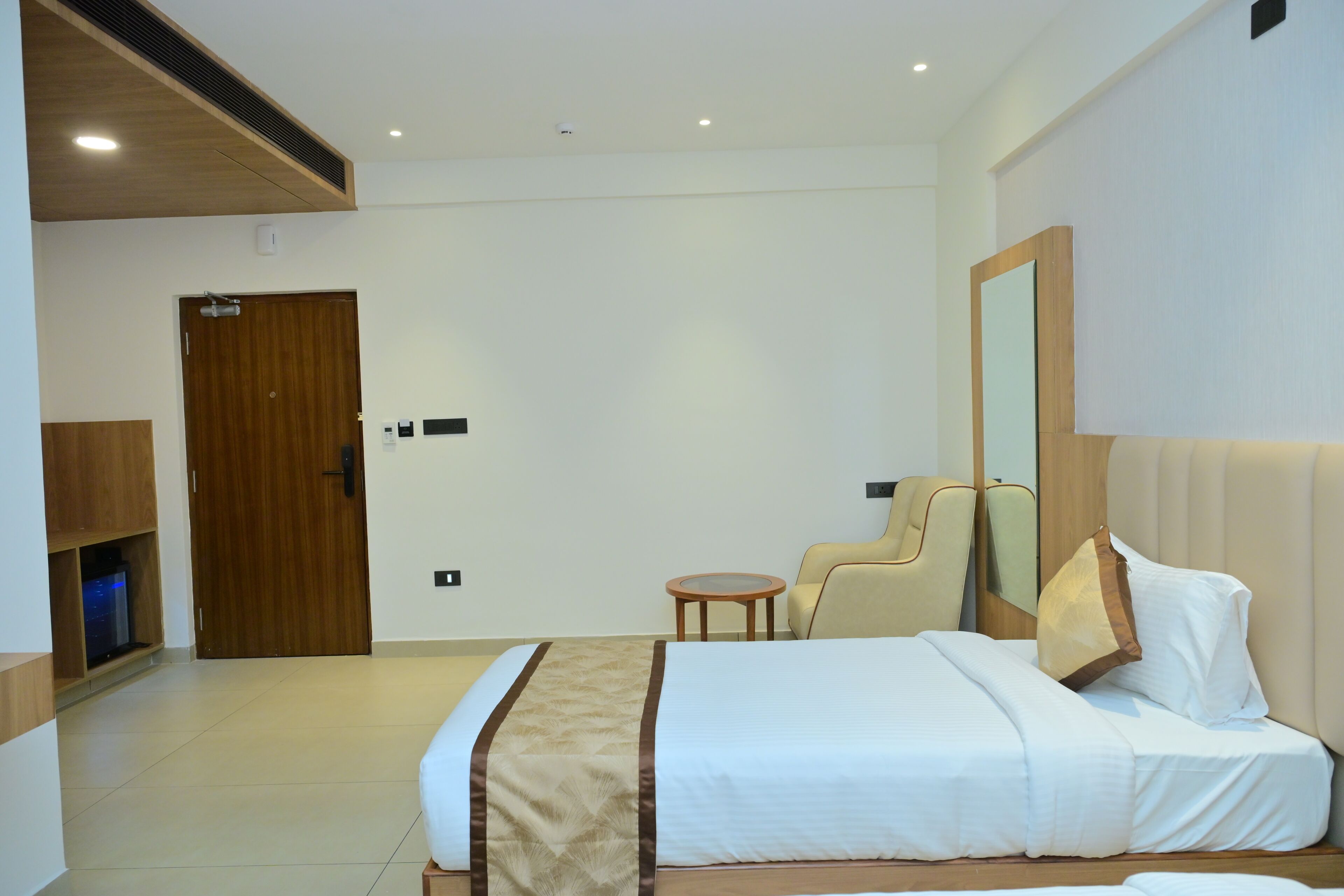 Une chambre d’hôtel avec un lit, une chaise, une petite table et une armoire.