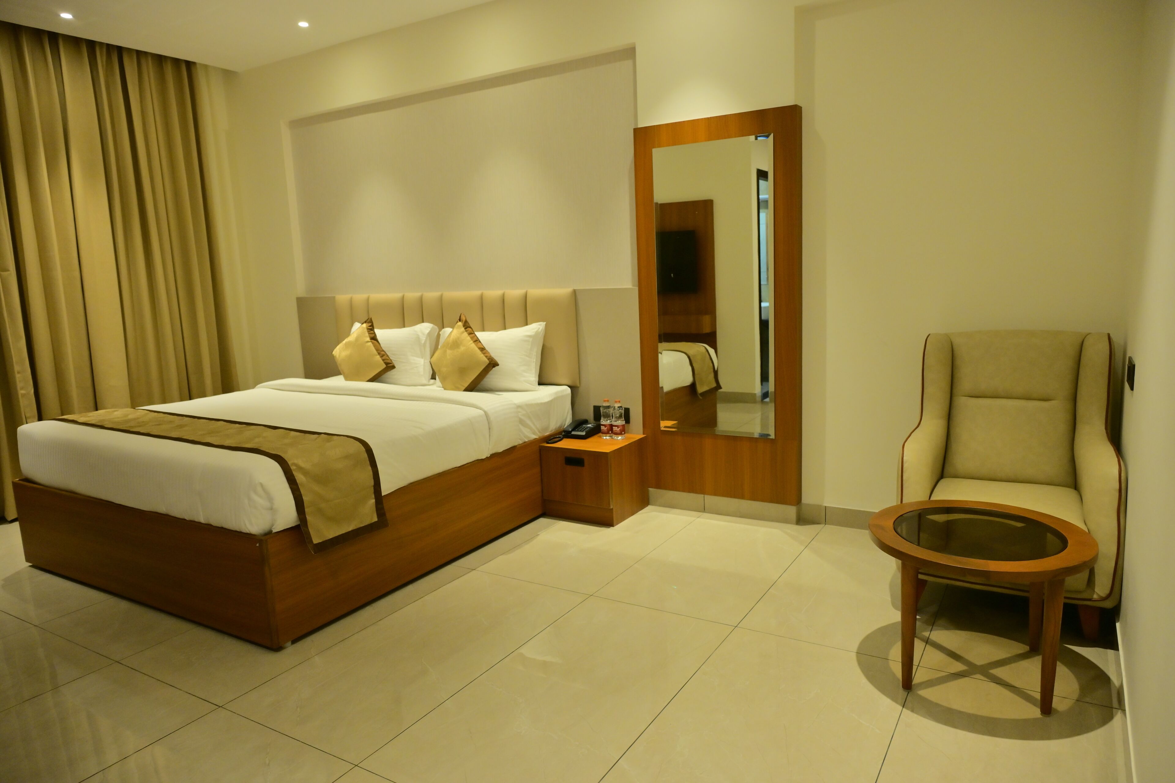 Una habitación de hotel con cama, mesita de noche, silla y una pequeña mesa redonda.