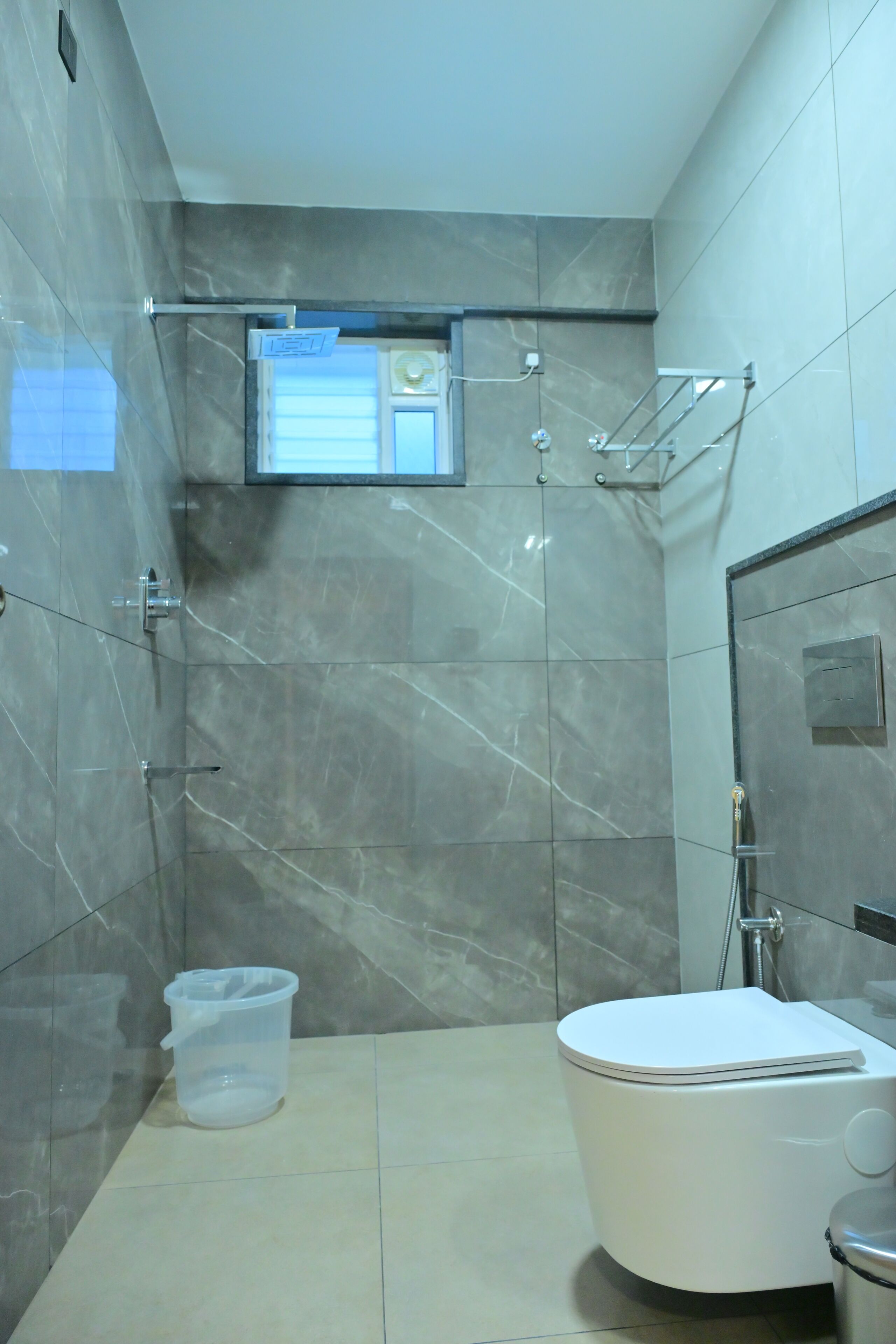 A bathroom with a toilet, a shower, and a small window.