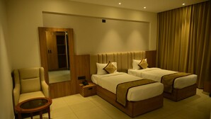 Una habitación de hotel con dos camas, una silla, una mesita y un espejo.