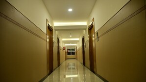 Un pasillo largo y estrecho con puertas a ambos lados, suelo brillante e iluminación empotrada en el techo.