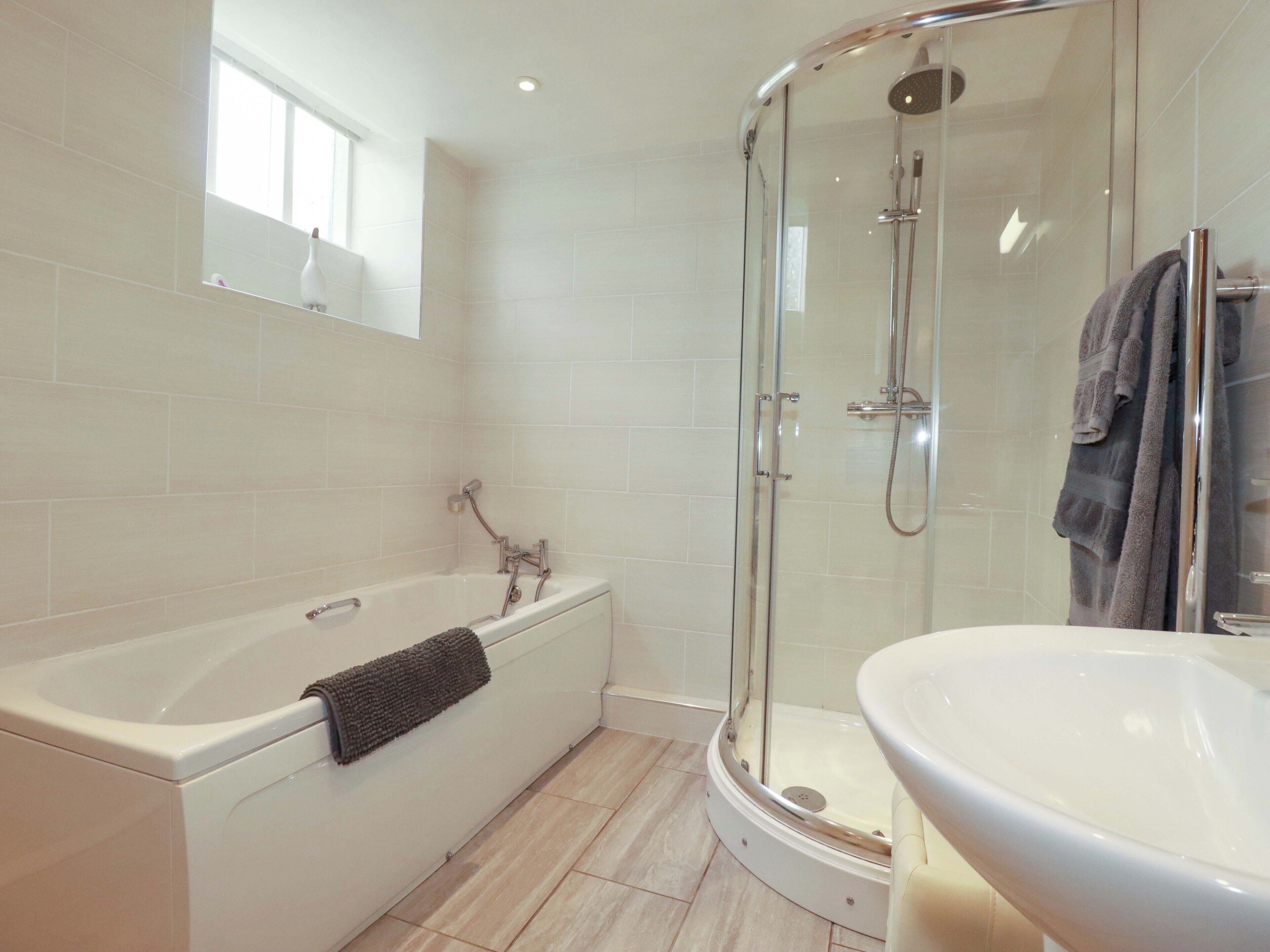 A modern bathroom with a bathtub, shower, and sink.