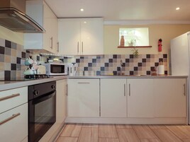 Una cocina moderna con armarios blancos, un microondas, un hervidor y un lavamanos.