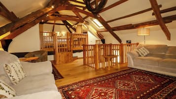 A loft-style room with exposed wooden beams, a red patterned rug, and a white sofa.