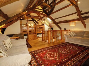 Un loft con vigas de madera a la vista, un tapete rojo con estampado y un sofá blanco.