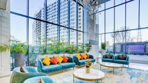 Un vestíbulo moderno con amplios ventanales, una zona de estar con sofás y sillones, y una mesa de centro.