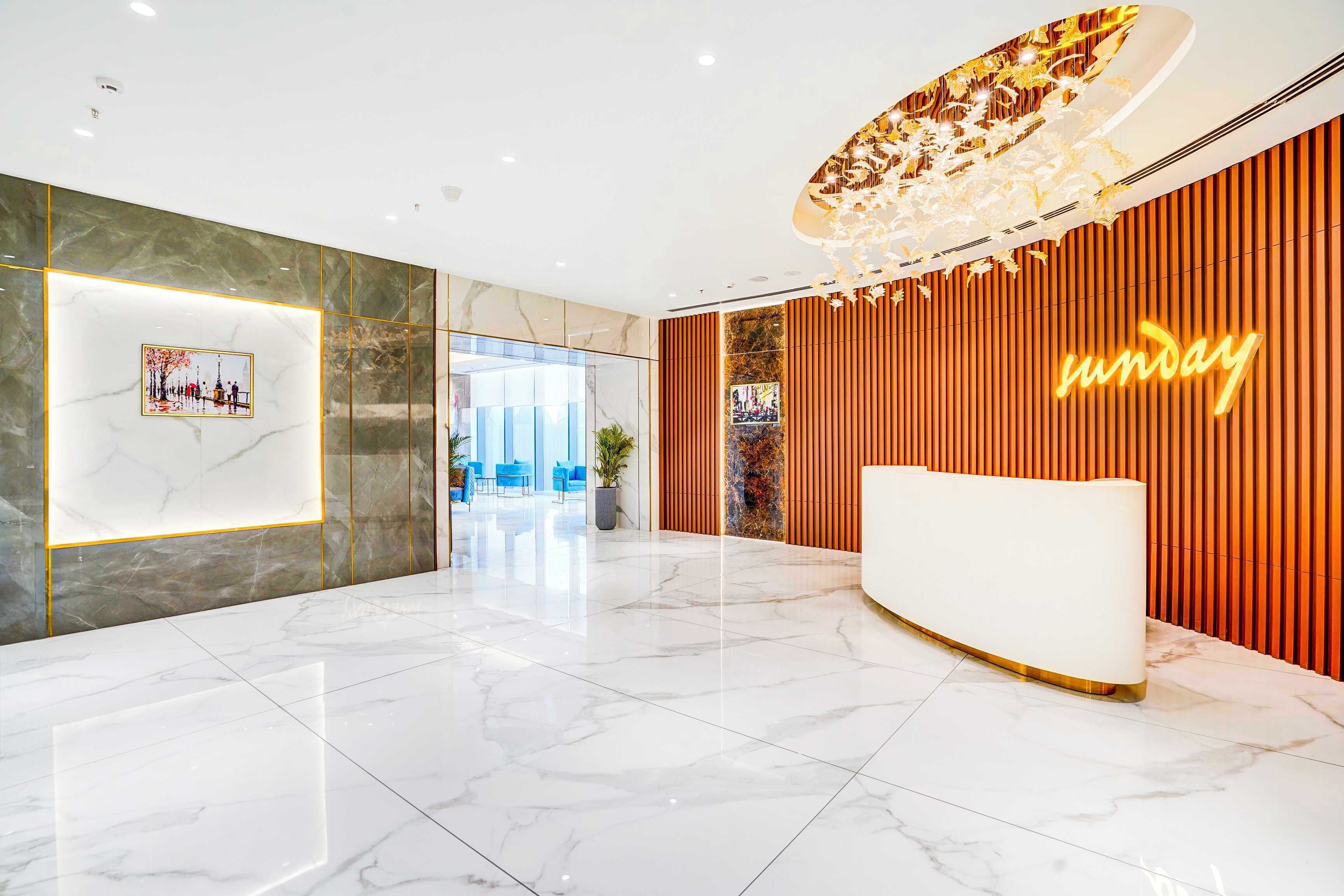Un hall d’entrée moderne avec un comptoir d’accueil, un sol en marbre et un grand lustre.