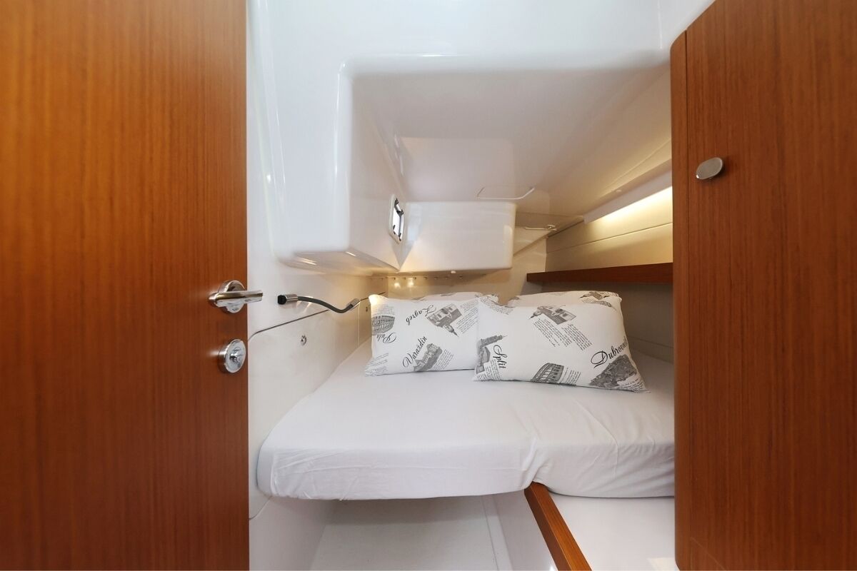 Ein kompaktes Kabinett mit Etagenbett, einer kleinen Ablage und einer Tür mit Griff.