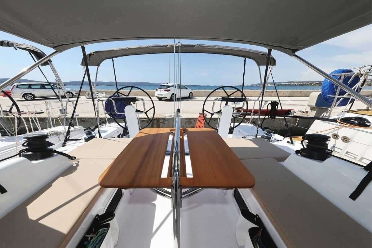 A boat deck with a central table, steering wheel, and a view of the marina and sea.