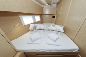 A compact, well-lit room with a bed, two pillows, and neatly folded towels. - Sibenik Sun-soaked Sailing: A Luxurious Croatian Voyage (Pirovac)