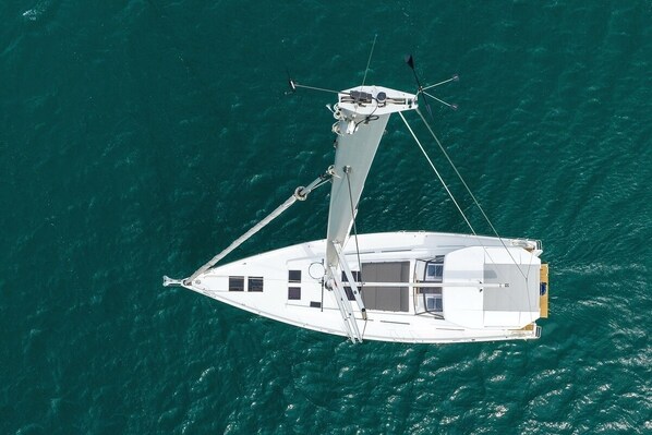 Un yacht blanc, doté d’une cabine, d’un mât et d’une voile, voguant sur une eau turquoise.