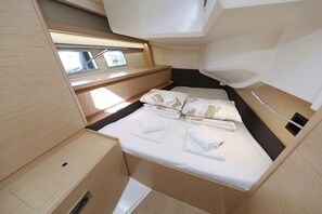 Une cabine compacte et bien éclairée, équipée d’un lit, de compartiments de rangement et d’une petite fenêtre.