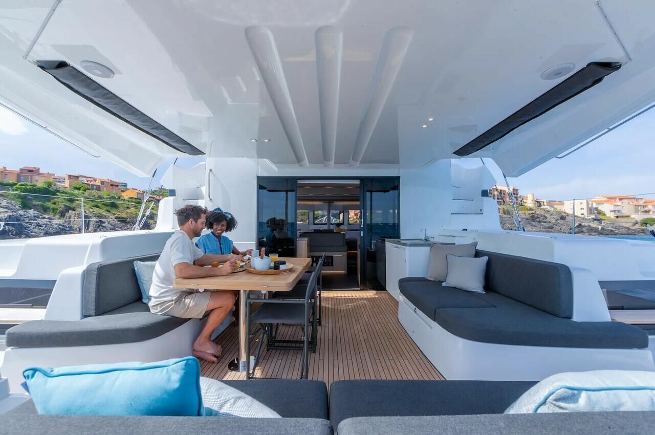 Um deck aberto com assentos e área de refeições, cozinha e vista para edifícios.